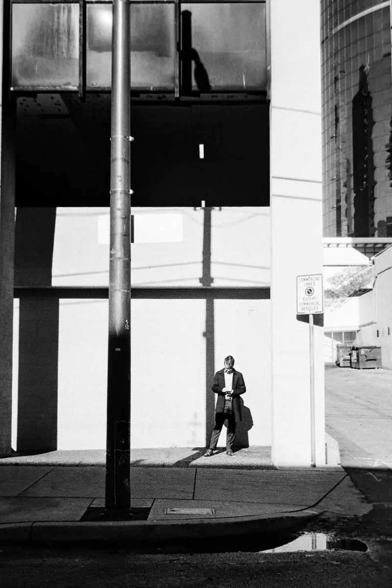 Man reading on his phone against a wall analog picture