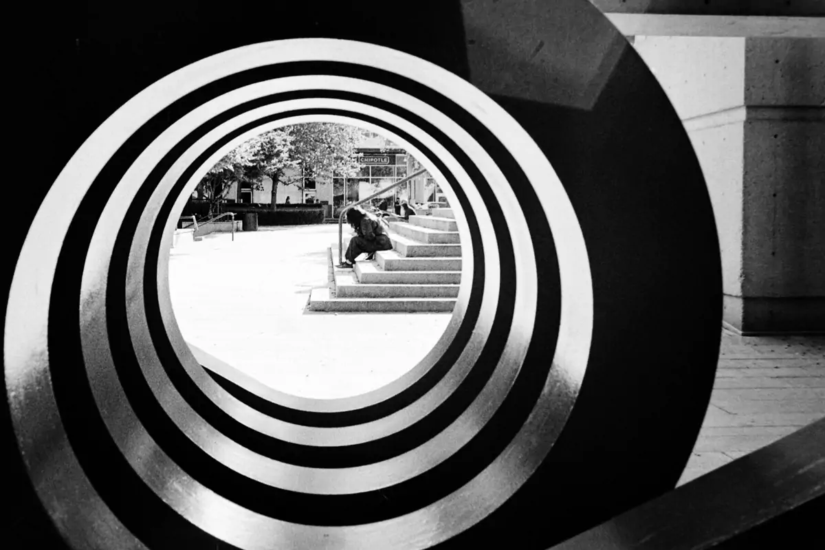 Pedestrian sitting on strairs view through a structure Analog photography